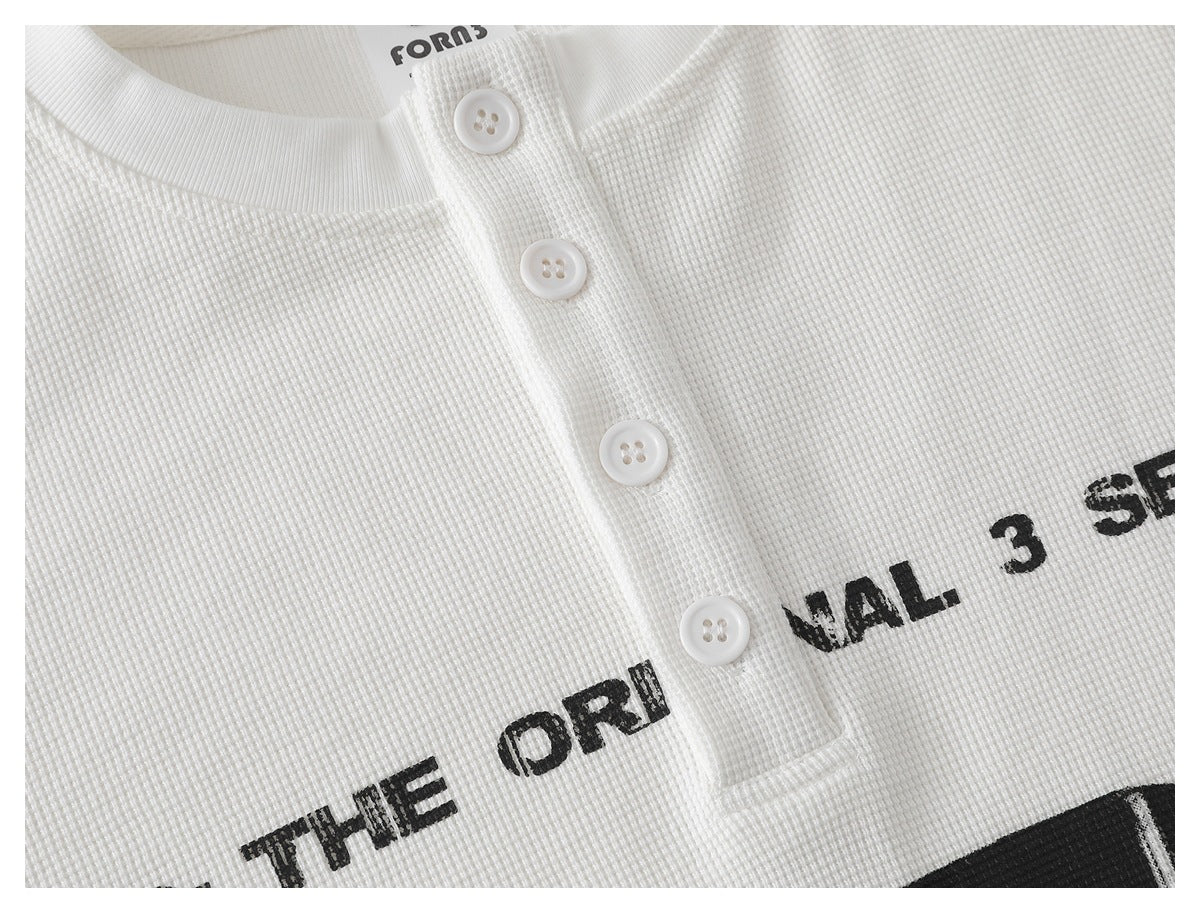 Close-up of a white waffle-knit shirt's ribbed collar and four-button placket, with partial black lettering.