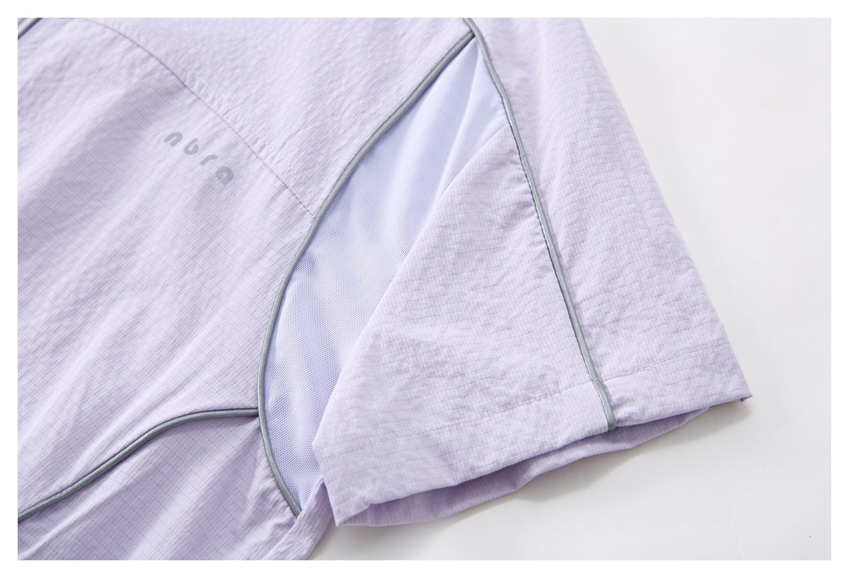 Close-up of a pale lilac top showing a gray-piped mesh panel, sleeve, and small chest mark.
