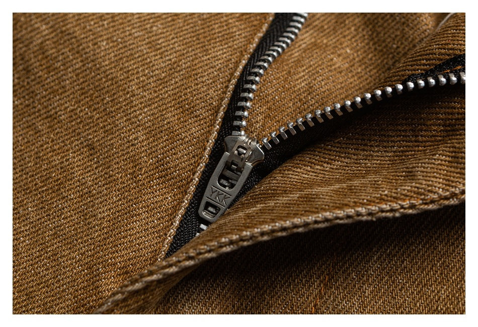 Close-up of a metal zipper on brown pants, with the zipper teeth and pull visible.