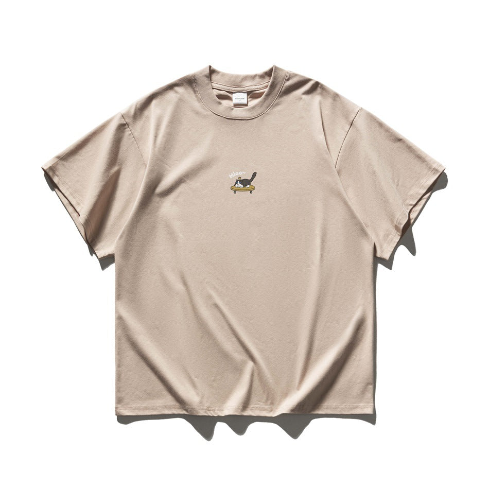 Beige-pink short-sleeve crew-neck T-shirt flat lay with a small cat-on-skateboard chest print