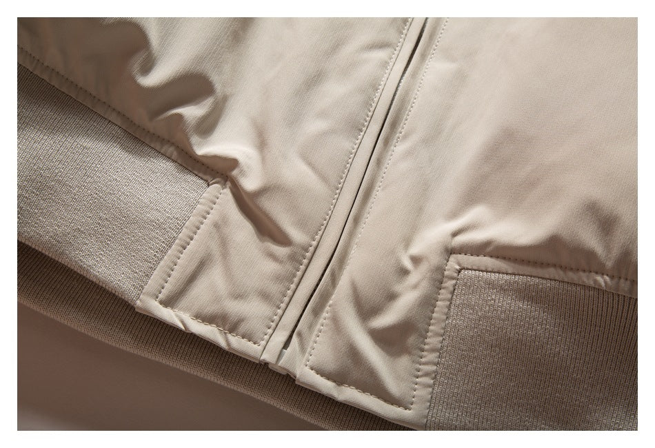 Close-up of a beige jacket's front zipper, ribbed hem, and ribbed cuff.