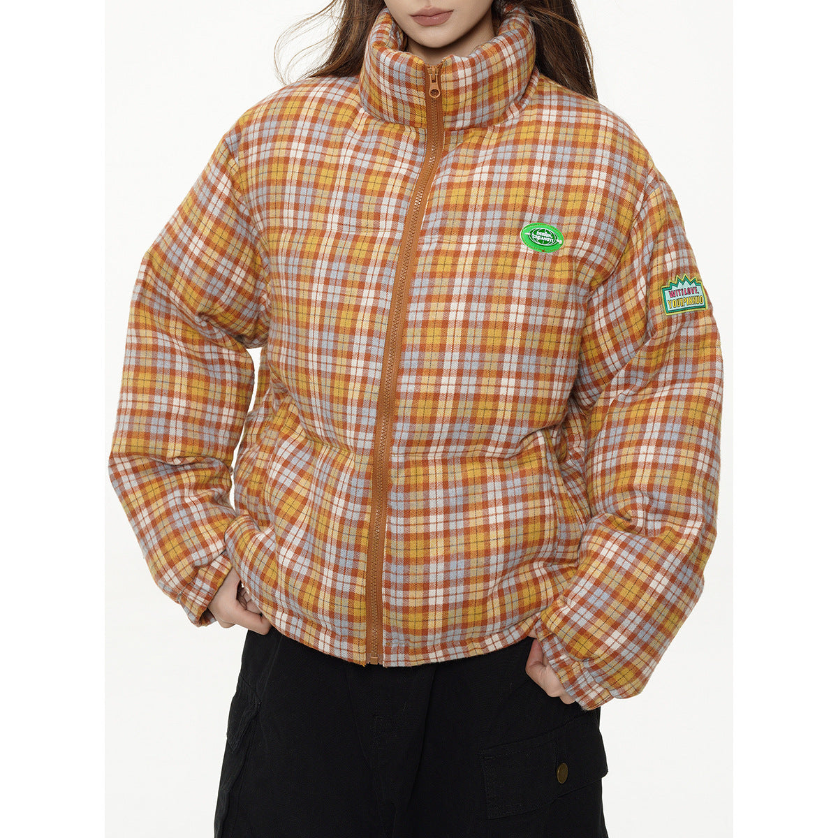 Close view of a model wearing an orange plaid puffer jacket with a brown zipper and chest and sleeve patches.