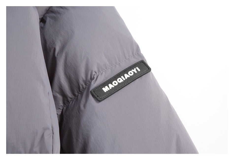 Close-up of a gray padded sleeve with a black rectangular text patch and stitched seam.