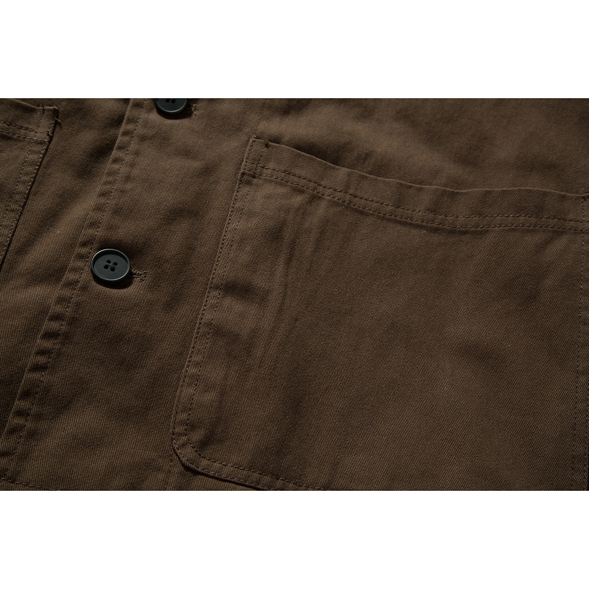 Close-up of a dark brown shirt's single chest pocket and black buttons.
