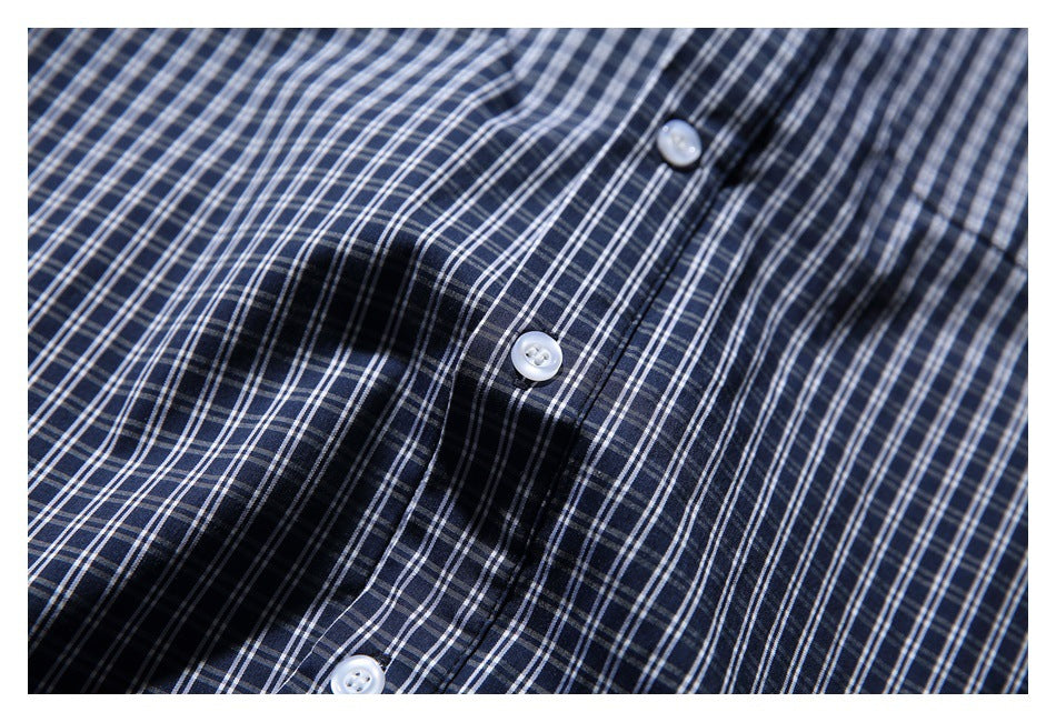 Close-up of white buttons and the front placket on a navy-and-white plaid shirt.