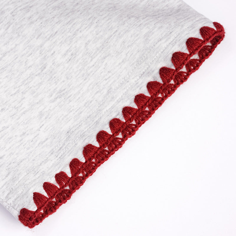 Close-up of a light gray T-shirt sleeve finished with dark red scalloped trim.