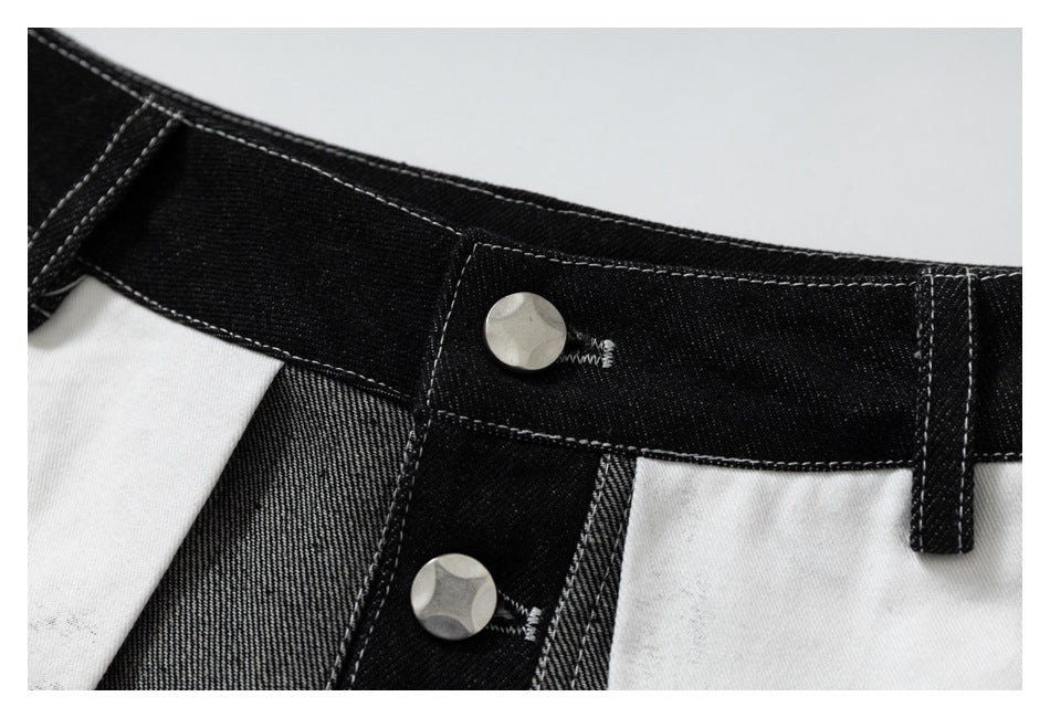 Close-up of the black waistband, belt loop, and silver buttons on the jeans' fly.
