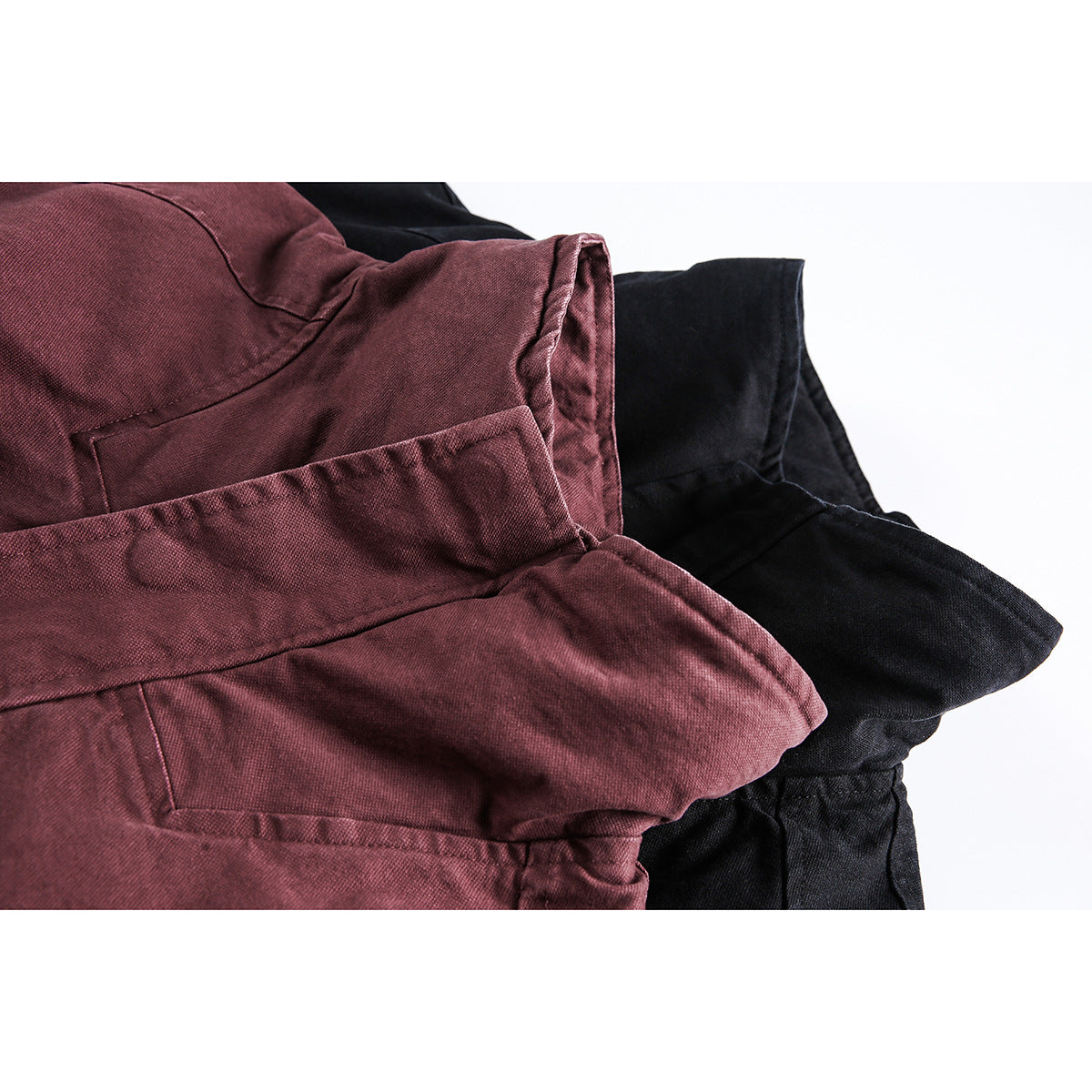 Close-up of burgundy and black jackets showing overlapping fabric panels and stitched seams.