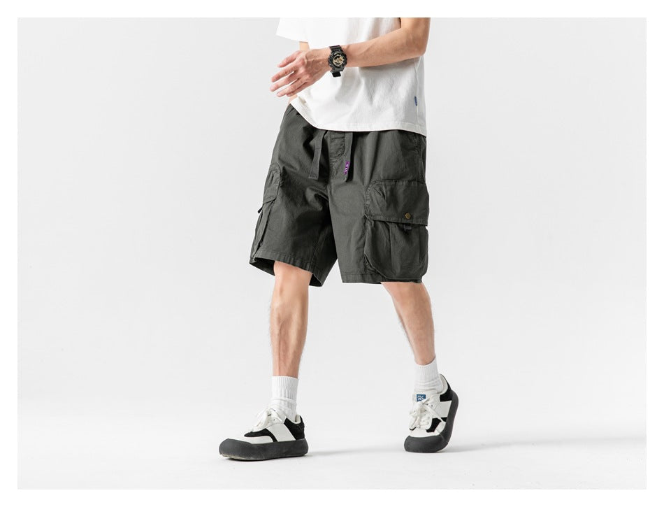 Model wearing dark charcoal cargo shorts with a drawstring waist and large side cargo pockets, shown at an angle.