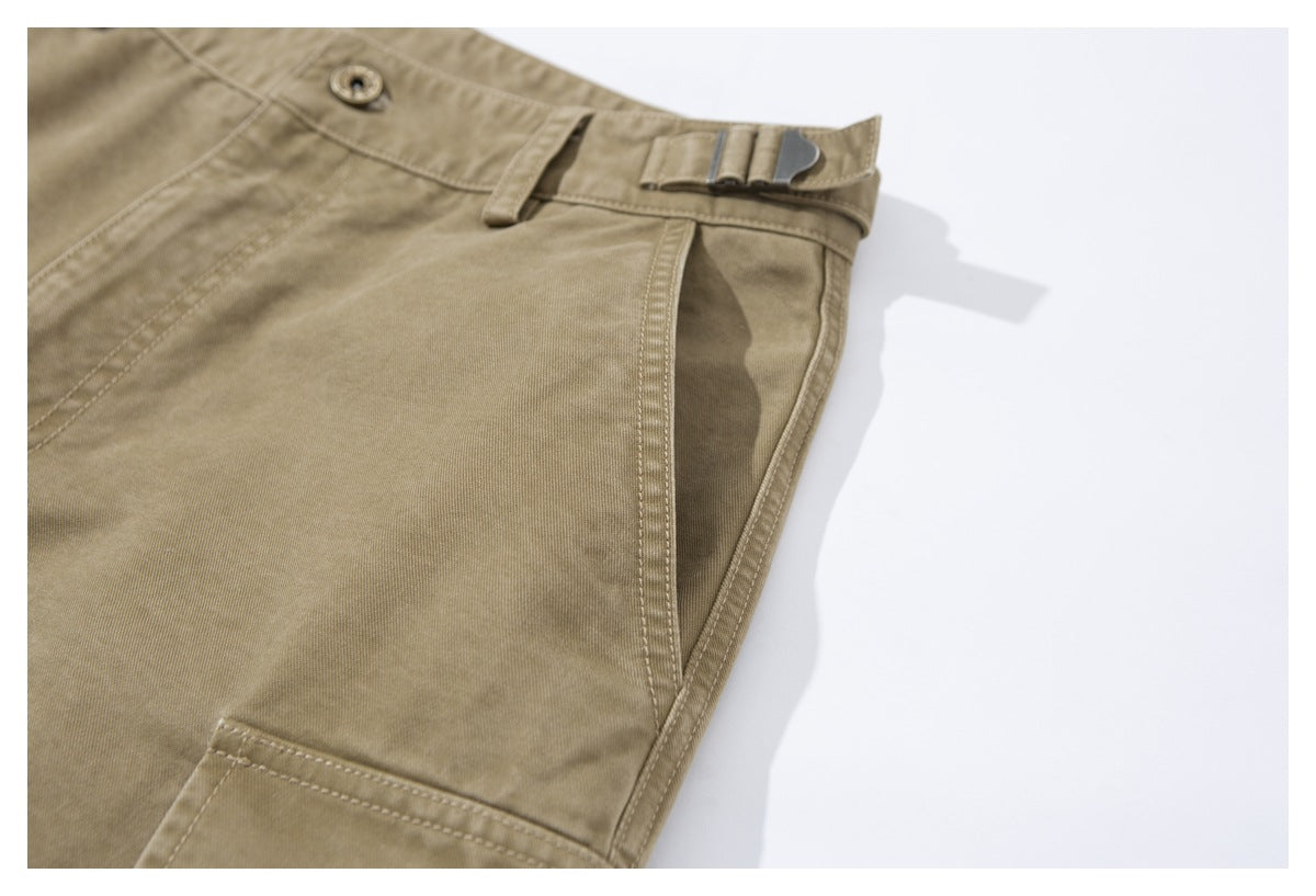 Close-up of khaki trousers showing a slanted front pocket, waistband button, belt loop, and metal side adjuster.