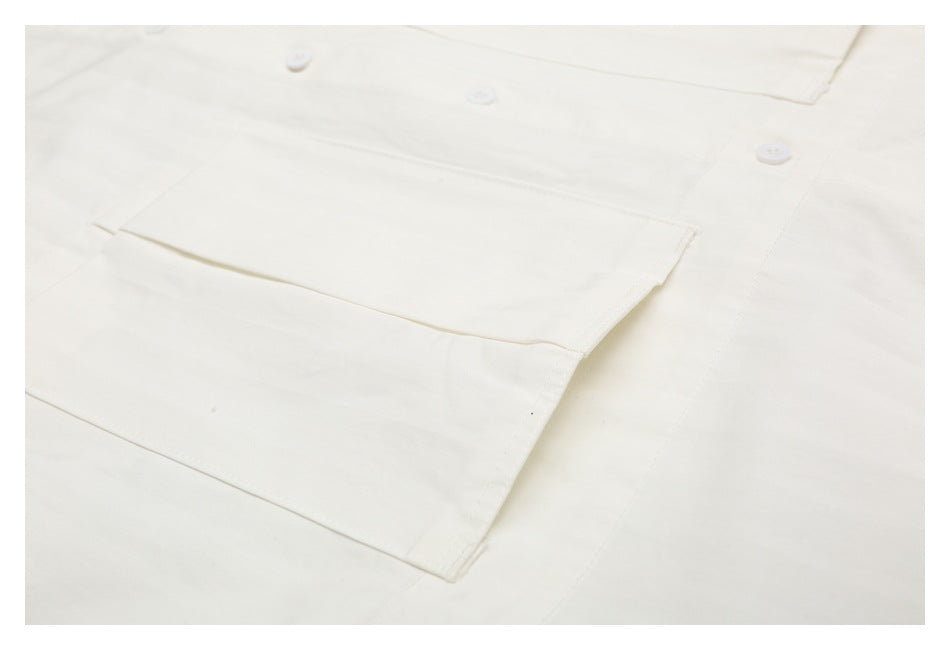 Close-up of a large patch pocket and buttons on an off-white shirt.