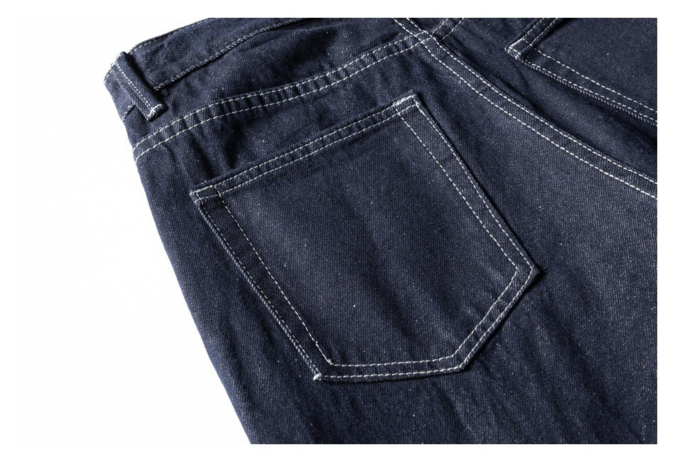 Close-up of a rear pocket and contrast stitching on dark indigo jeans.