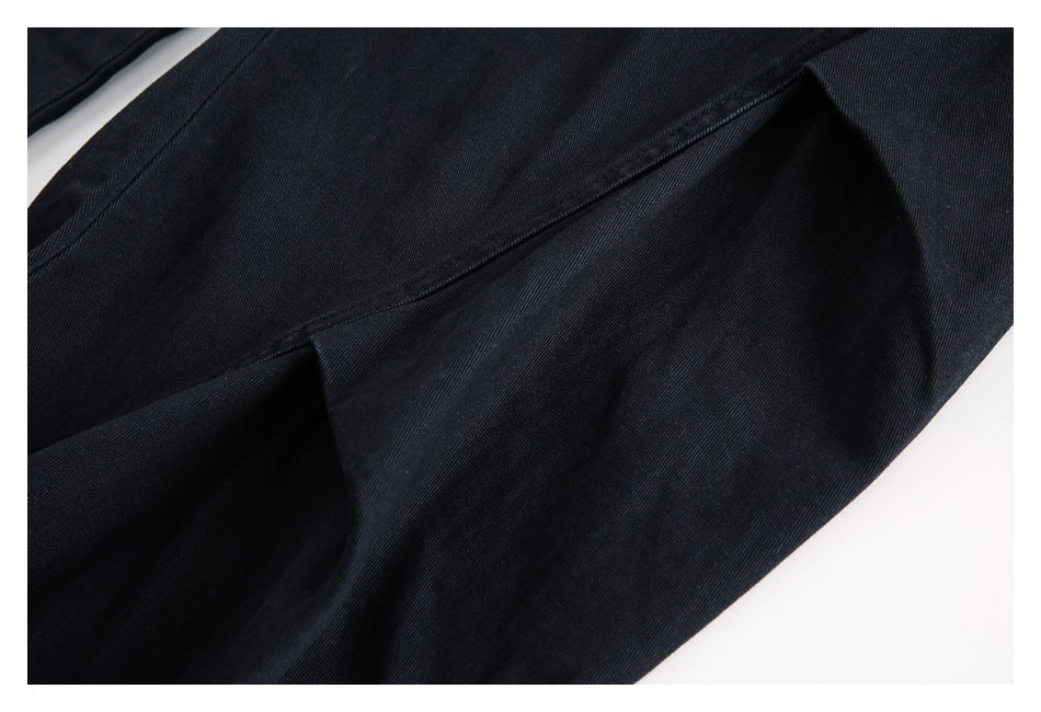 Close-up of black trouser fabric and stitching, showing a folded seam.