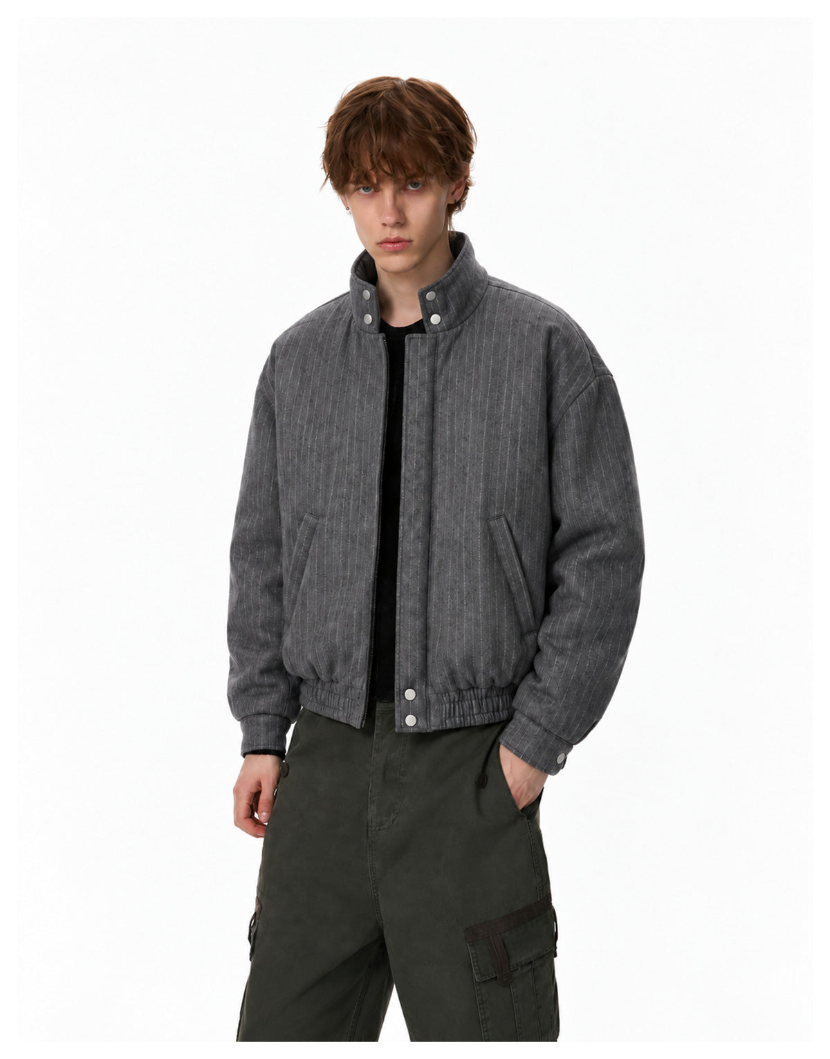 Model wearing a dark gray pinstriped bomber jacket with stand collar over a black top and green cargo pants