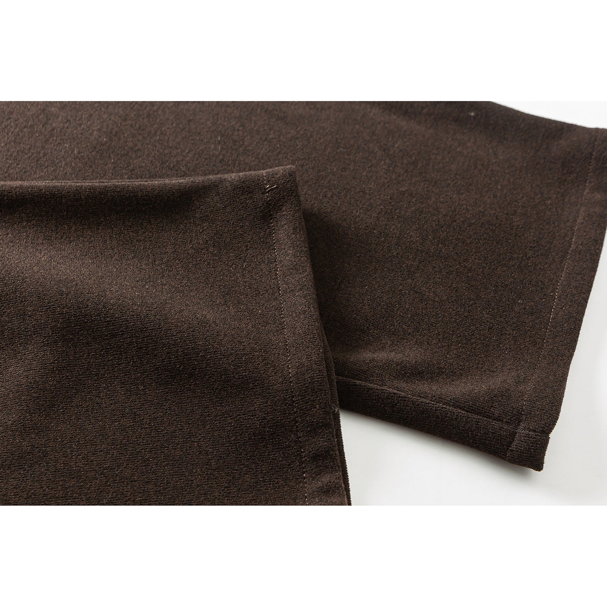 Close-up of the dark brown pants' wide legs and stitched hems.