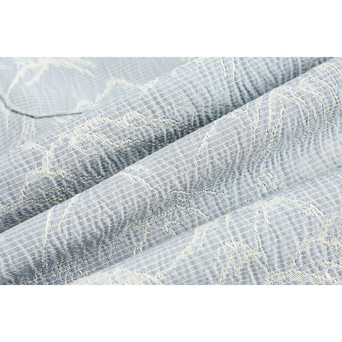 Extreme close-up of the textured pale blue and white woven pattern on the shorts.