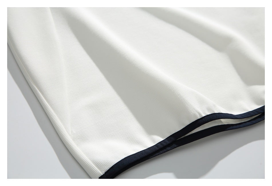 Close-up of the white ribbed shirt's hem finished with narrow black trim.
