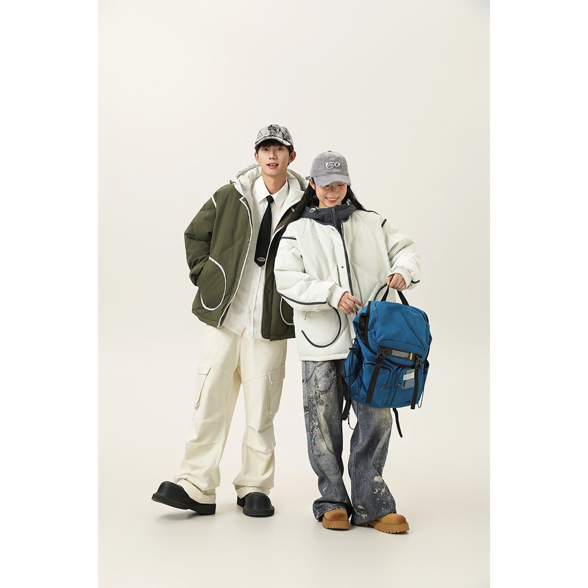 Two models wear oversized hooded jackets: one olive with white trim and one ivory with dark trim.