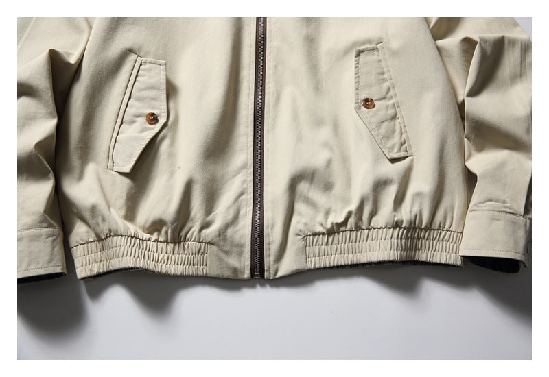 Close-up of the beige jacket's buttoned front pockets, center zipper, cuffs, and elasticized hem.