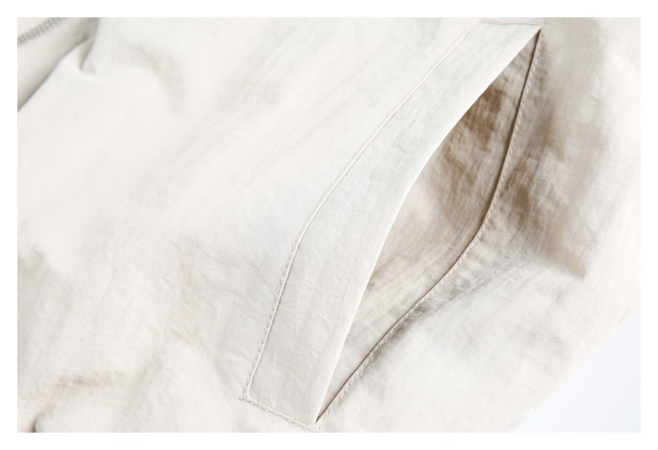 Close-up of a stitched pocket opening on light beige fabric.