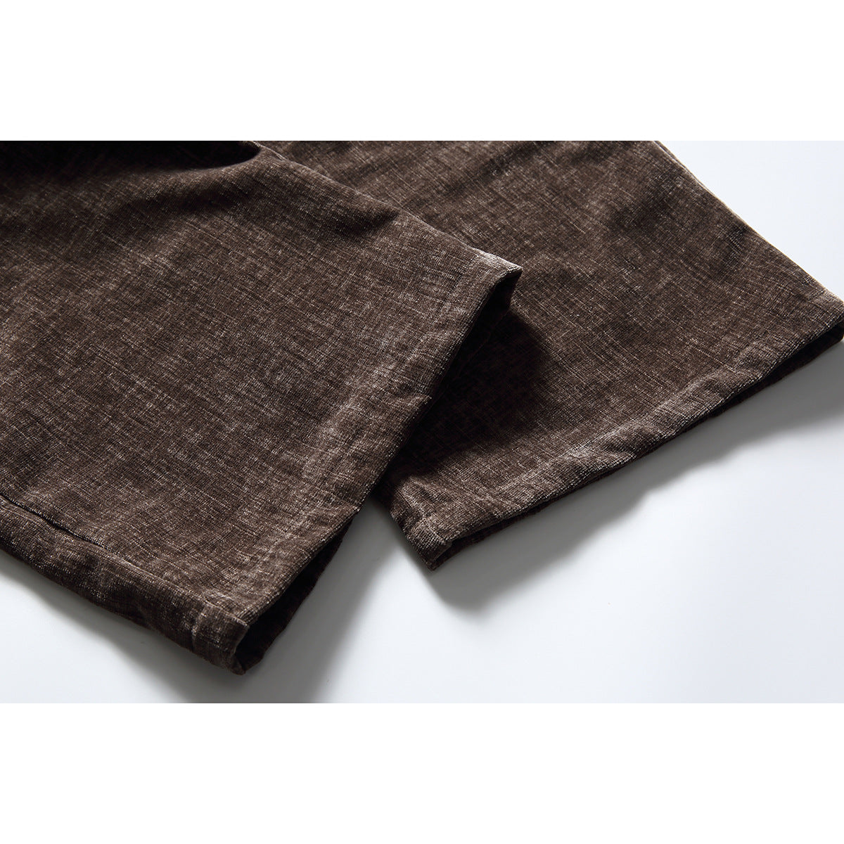 Close-up of the straight hems on brown textured trouser legs.