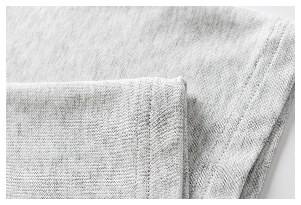 Close-up of a folded edge and parallel stitching on light gray heathered fabric.