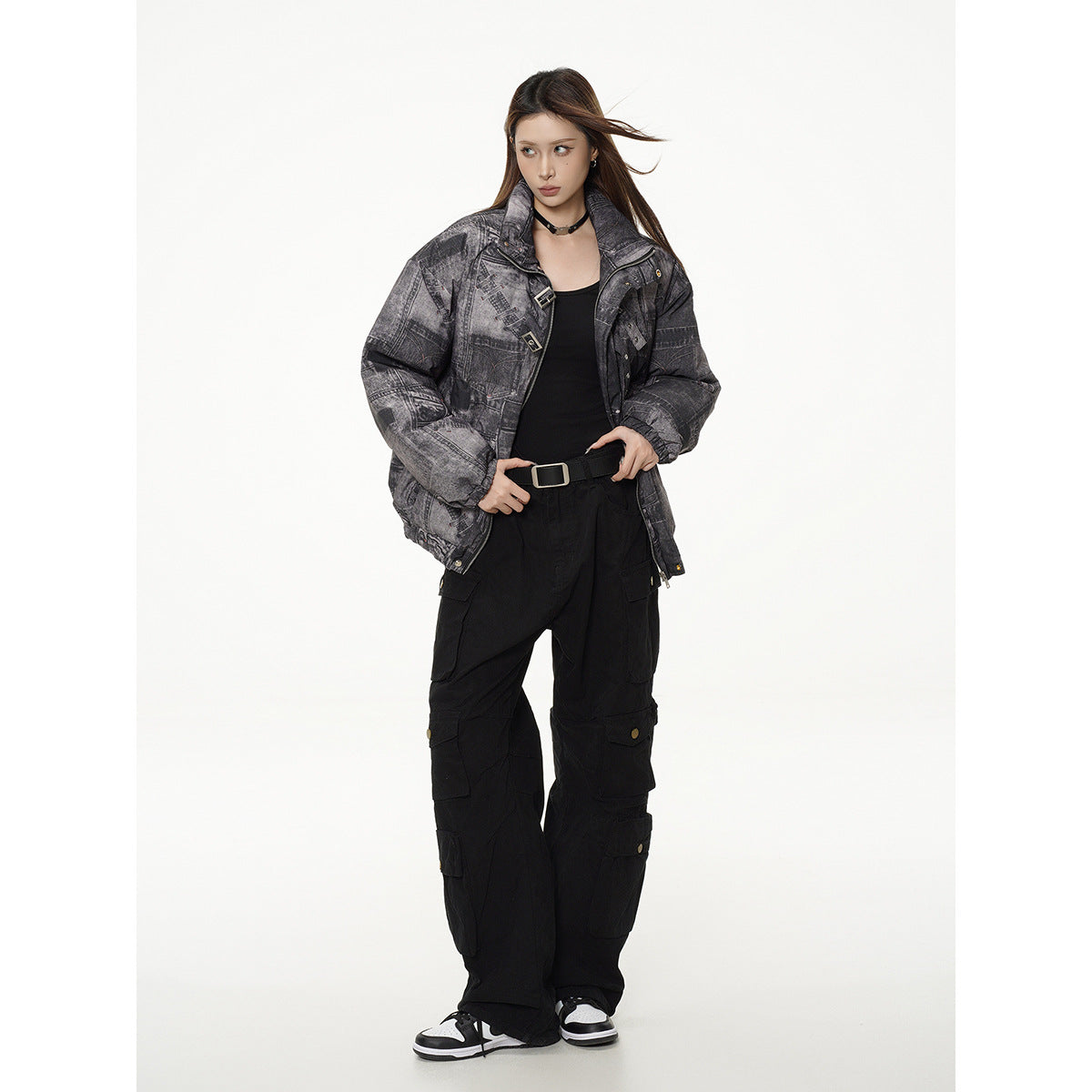 Full-length model wearing an open charcoal patchwork-print padded jacket with black cargo pants and sneakers.