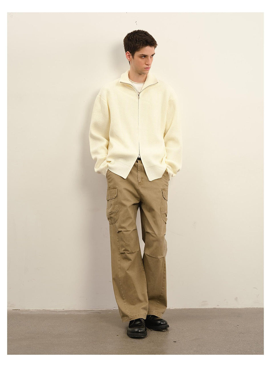 Model wearing an ivory ribbed zip-front cardigan with a stand collar and tan cargo trousers.