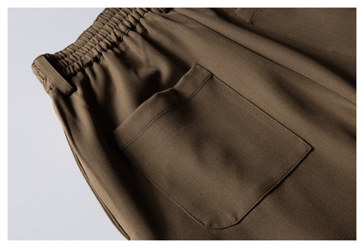 Close-up of brown trousers showing the elasticated waistband and a large stitched pocket.