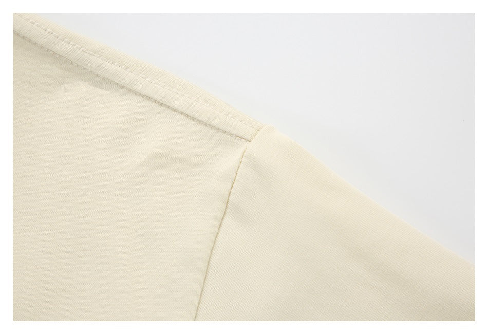 Close-up of the cream garment's shoulder seam and stitching.