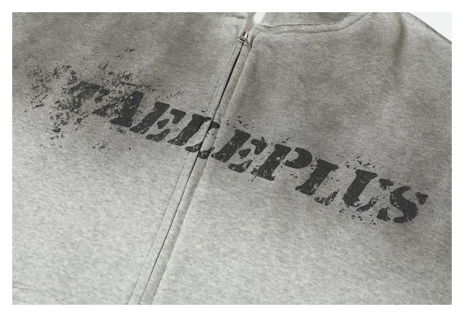 Close-up of distressed black lettering across the front of a heather-gray zip-up hoodie.