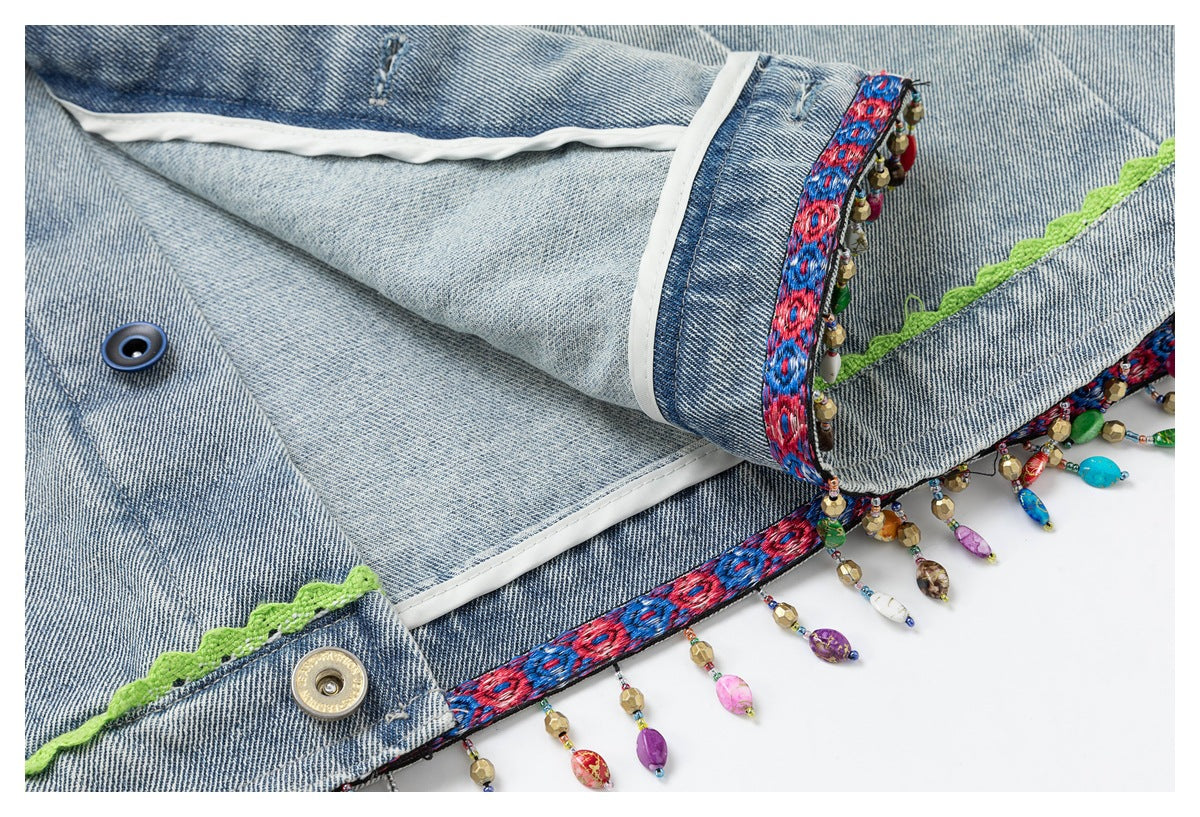 Inside view of light blue denim with white seam binding, colorful embroidered trim, bead fringe and buttons.