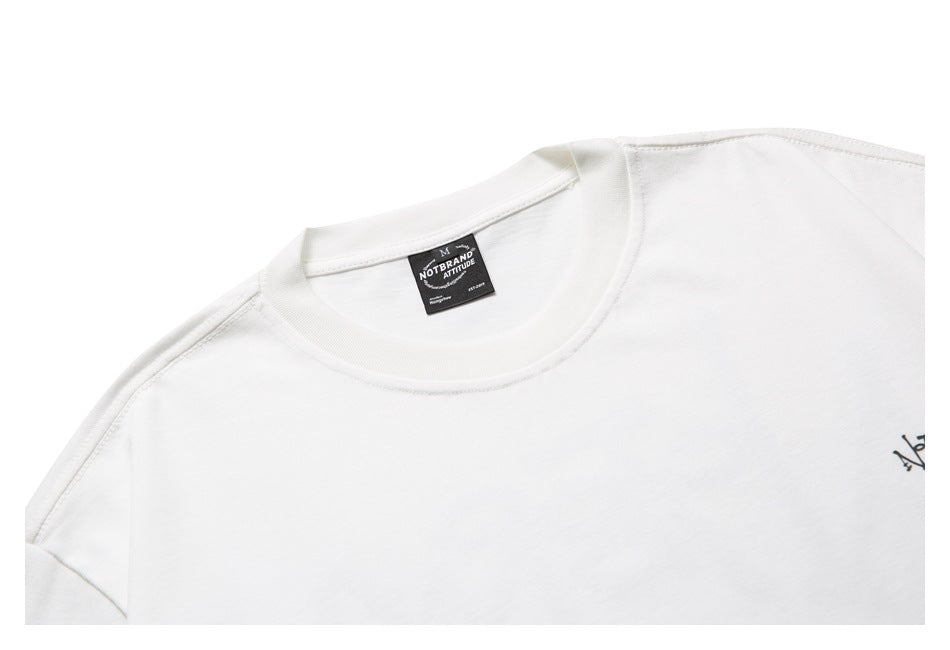 Close-up of the white T-shirt’s crew neckline, shoulder seam, and sewn-in black neck label.