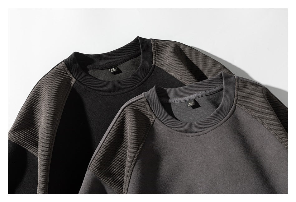 Two crewneck sweatshirts in black and charcoal, arranged together to show their textured shoulder panels and ribbed collars.