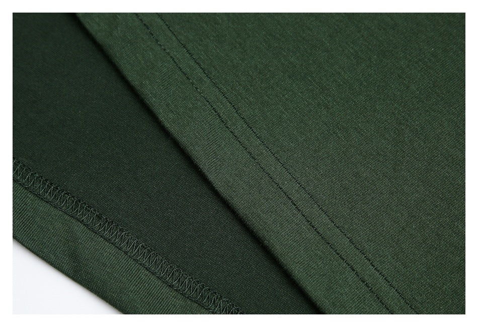 Close-up of dark green garment fabric with a stitched seam and overlocked edge.