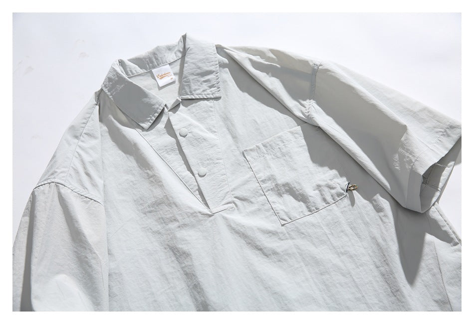 Front view of a light gray collared pullover laid flat, with short sleeves, a button placket, and a chest pocket.