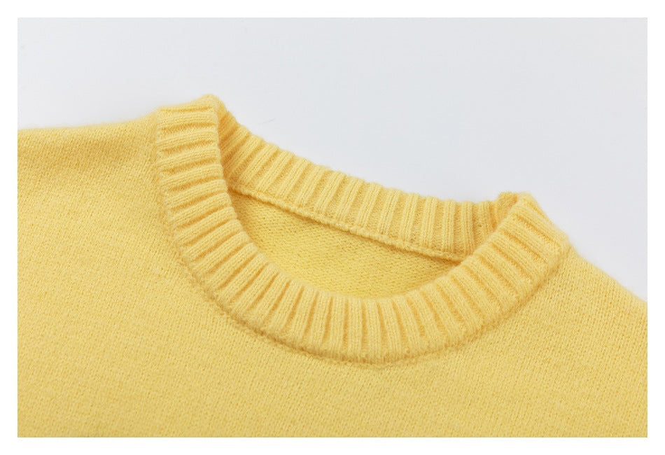Close-up of the pale yellow sweater's ribbed crew neckline and knit texture.