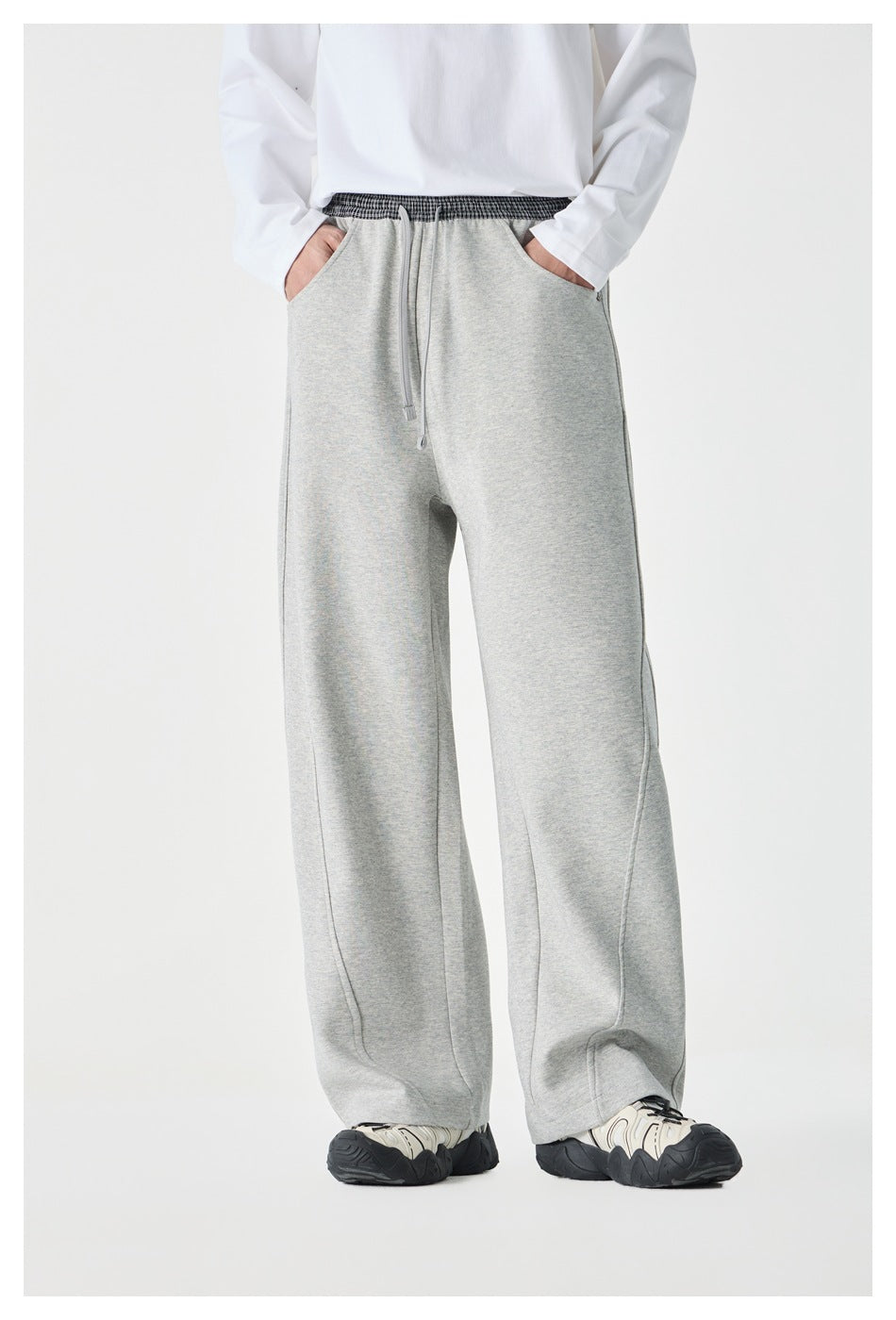 Front view of a model wearing light gray wide-leg pants with a checked waistband, drawstring, and side pockets.