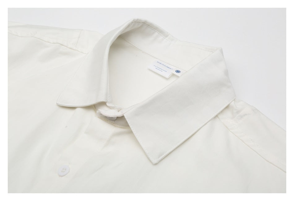 Close-up of an off-white shirt collar, neckline label, and top button.