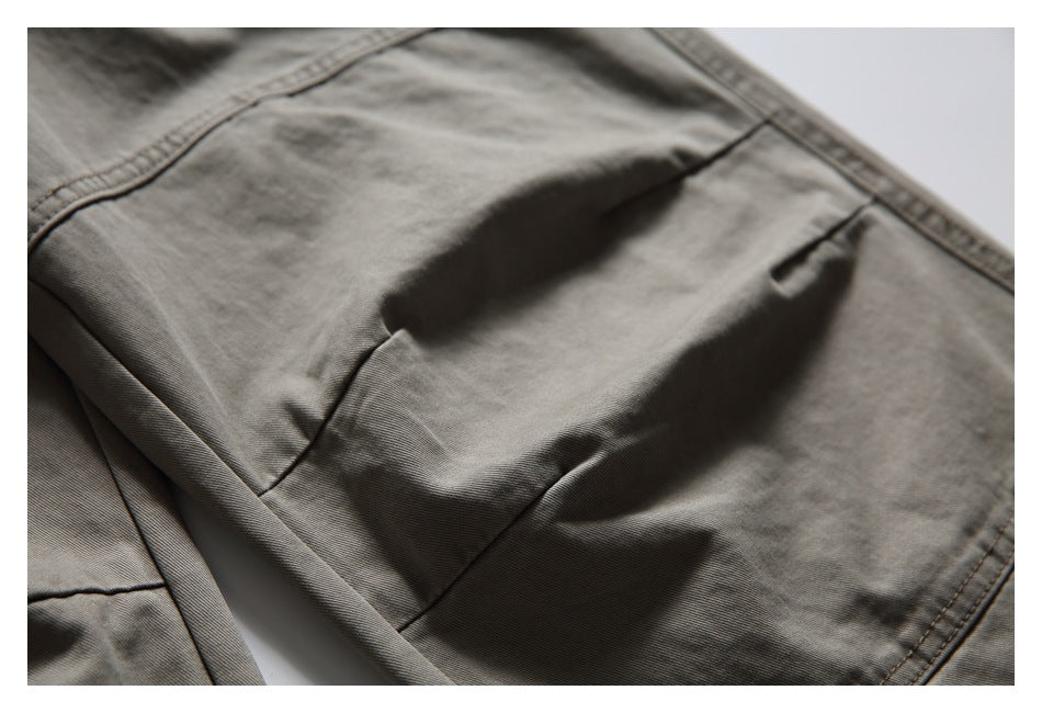 Close-up of a stitched cargo pocket on gray-olive pants.