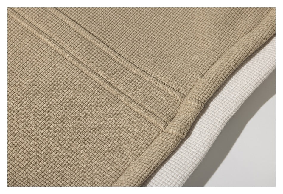 Close-up of a beige jacket's stitched edge with a strip of white fabric beneath.