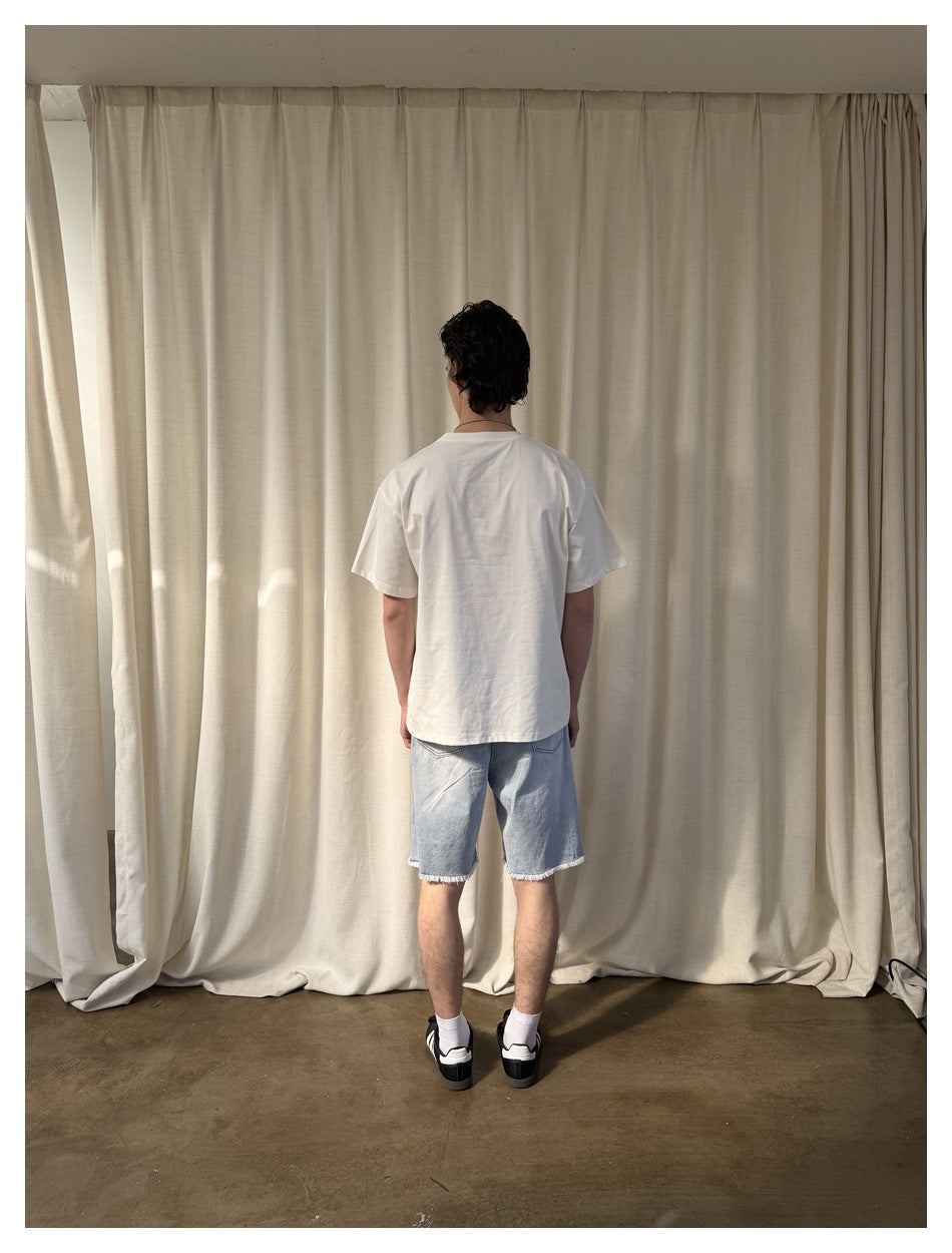 Back view of a model wearing a plain white T-shirt and light blue cutoff denim shorts.