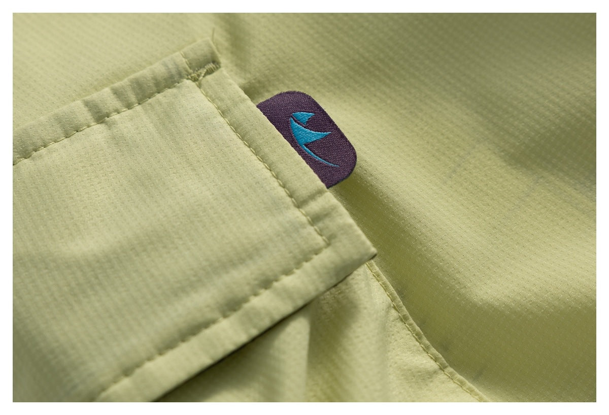 Close-up of a pale yellow garment pocket with a small purple tab and blue emblem.