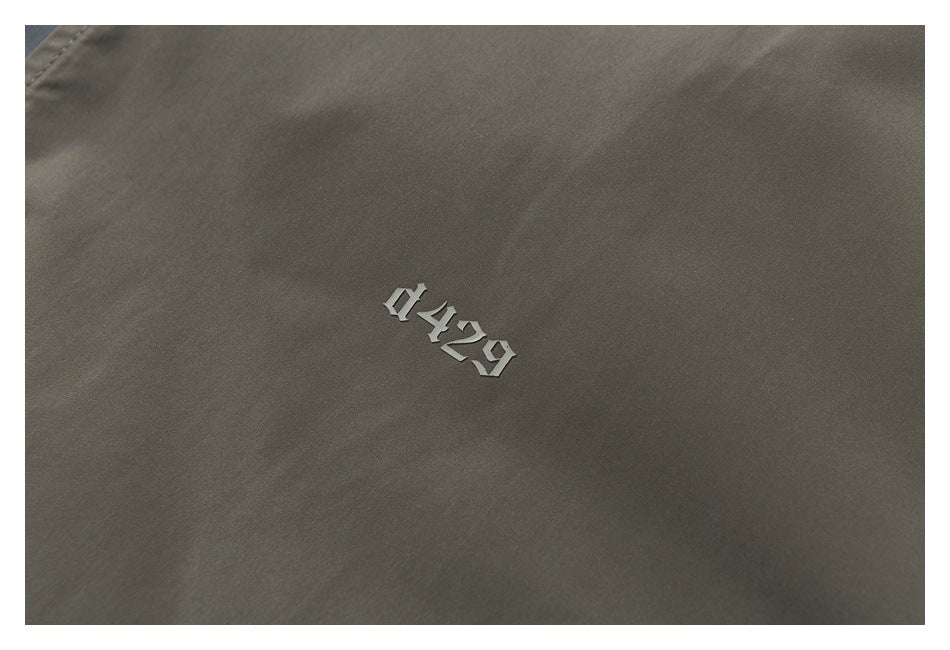 Close-up of gray-olive garment fabric with a small raised silver 0429 marking.