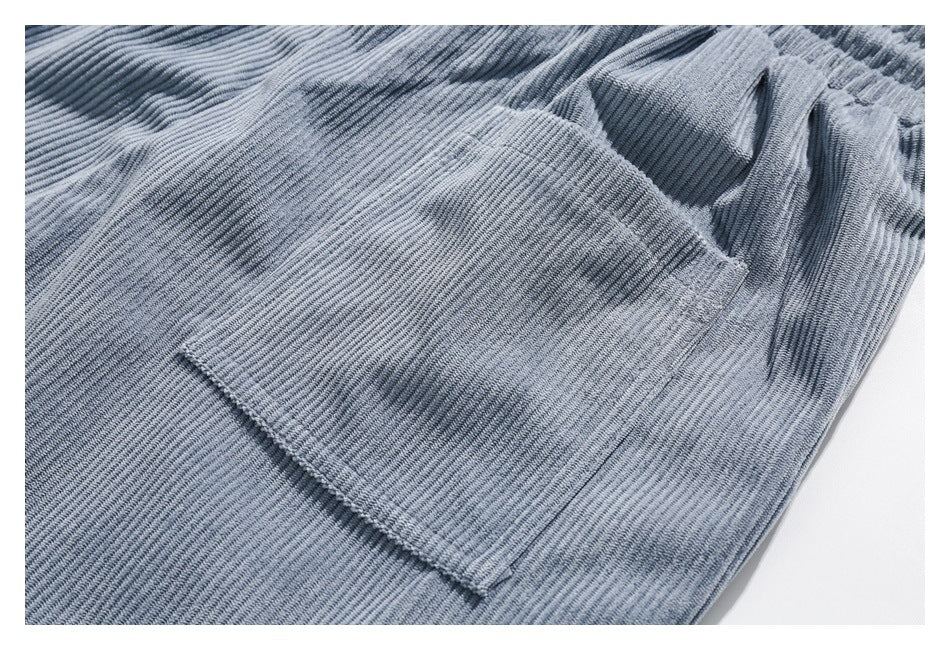 Close-up of a rectangular patch pocket on light blue ribbed pants.