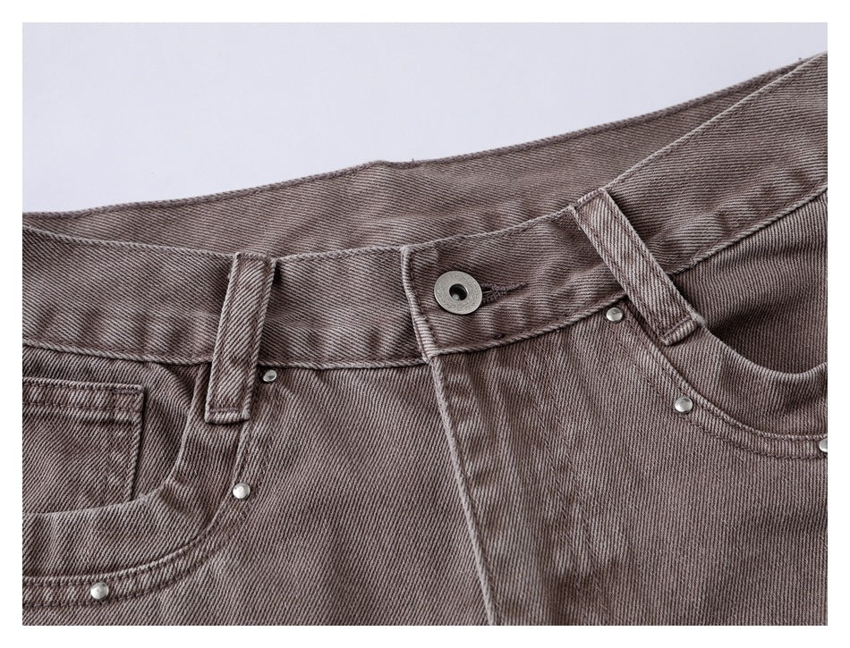 Close-up of the taupe jeans’ front waistband, metal button, belt loops, fly stitching and riveted pocket edge.