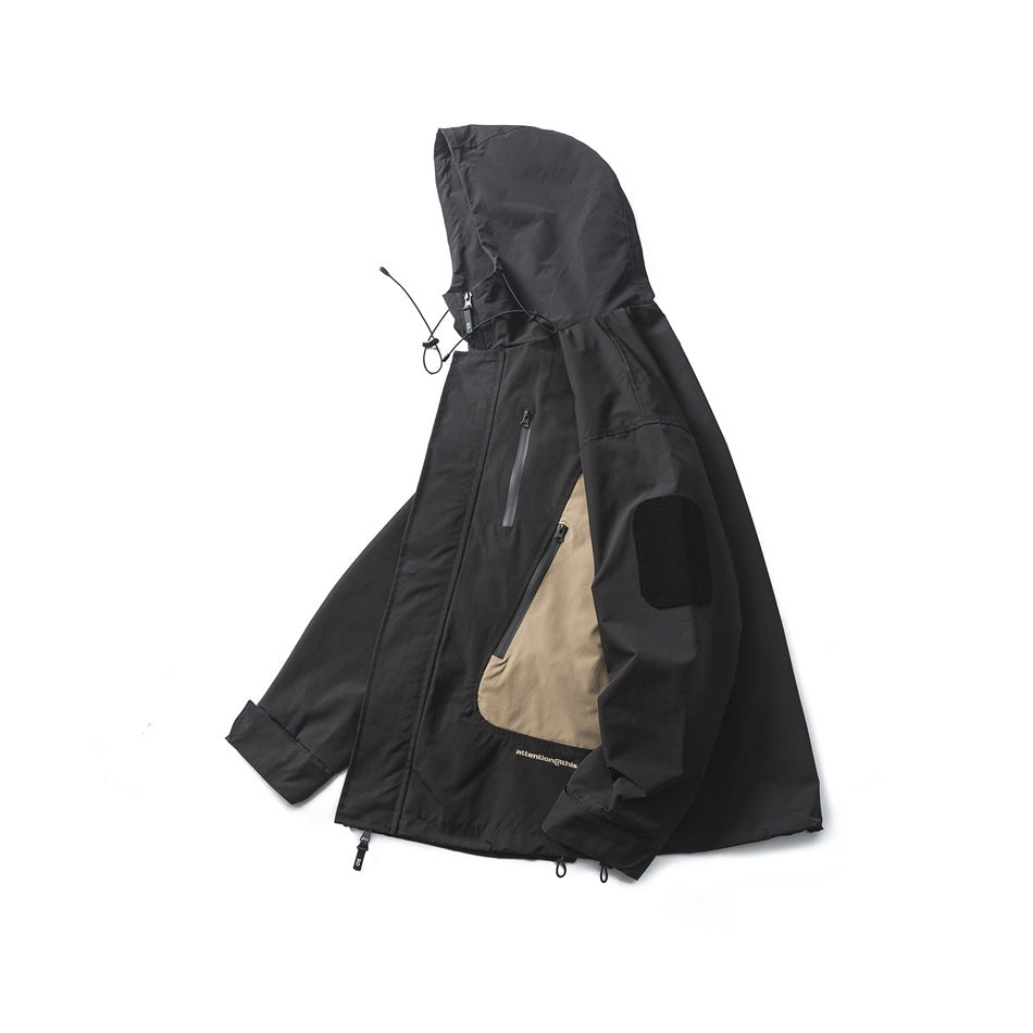Angled front view of a black hooded jacket with tan side panels, zip pockets, and a sleeve patch.