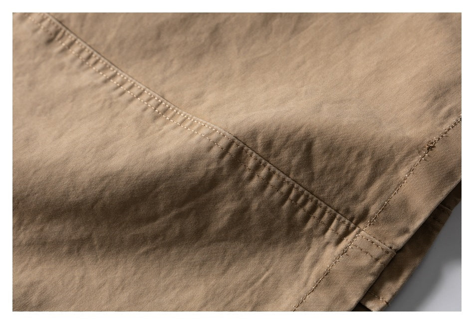 Close-up of tan garment fabric with intersecting stitched seams and a finished edge.