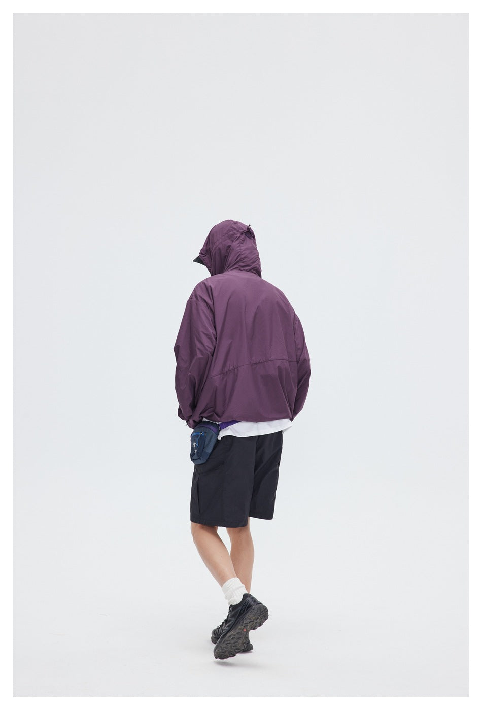 Rear view of a model wearing the plum hooded jacket and black shorts.