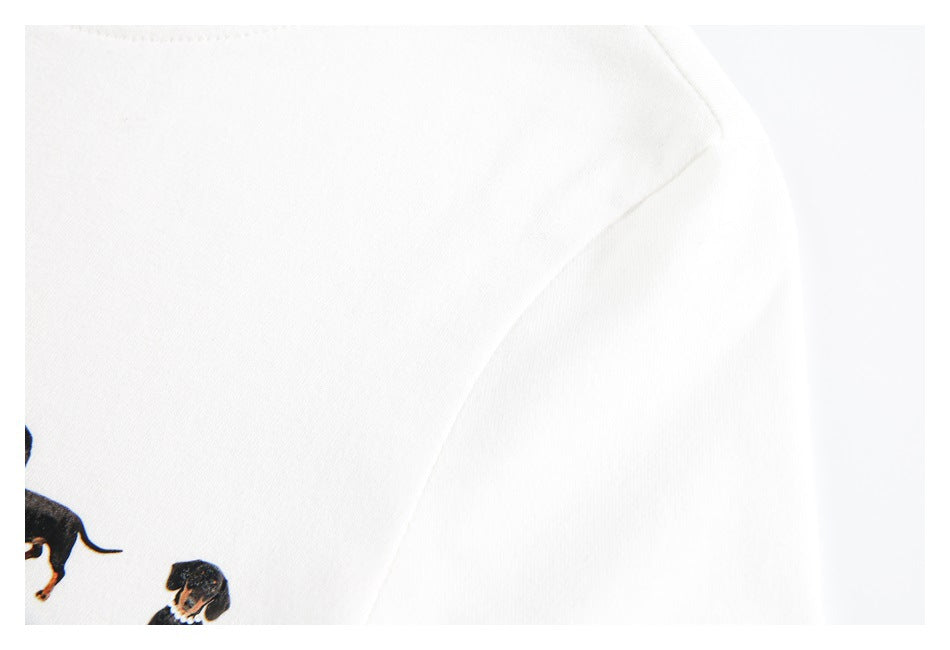 Close-up of the white T-shirt's shoulder seam, with part of the dachshund print visible at the edge.